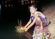 Thailand: Young girl floating a krathong on the moat in Chiang Mai's old town, Loy Krathong Festival